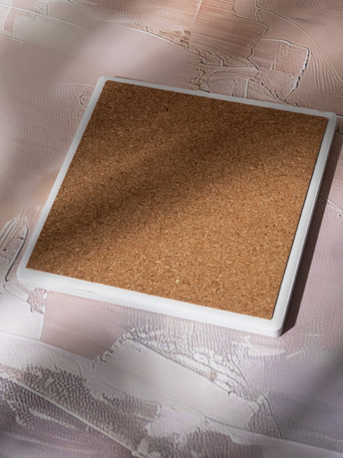 Square ceramic coaster featuring a detailed Art Deco peacock design in copper tones, surrounded by shell motifs and geometric fan patterns on a dark charcoal background, with protective cork base.